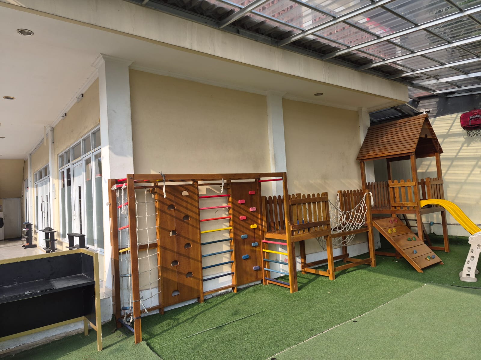 Area bermain anak dengan rumah kayu, perosotan, dan panjat dinding