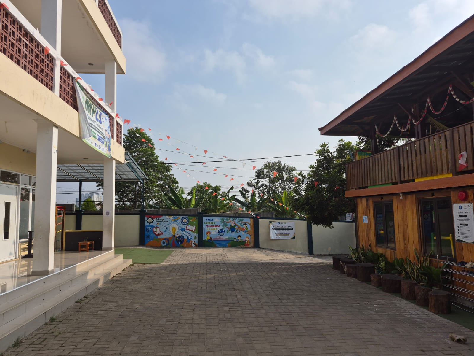 Halaman luas Saung Qur'an dengan mural dan pepohonan