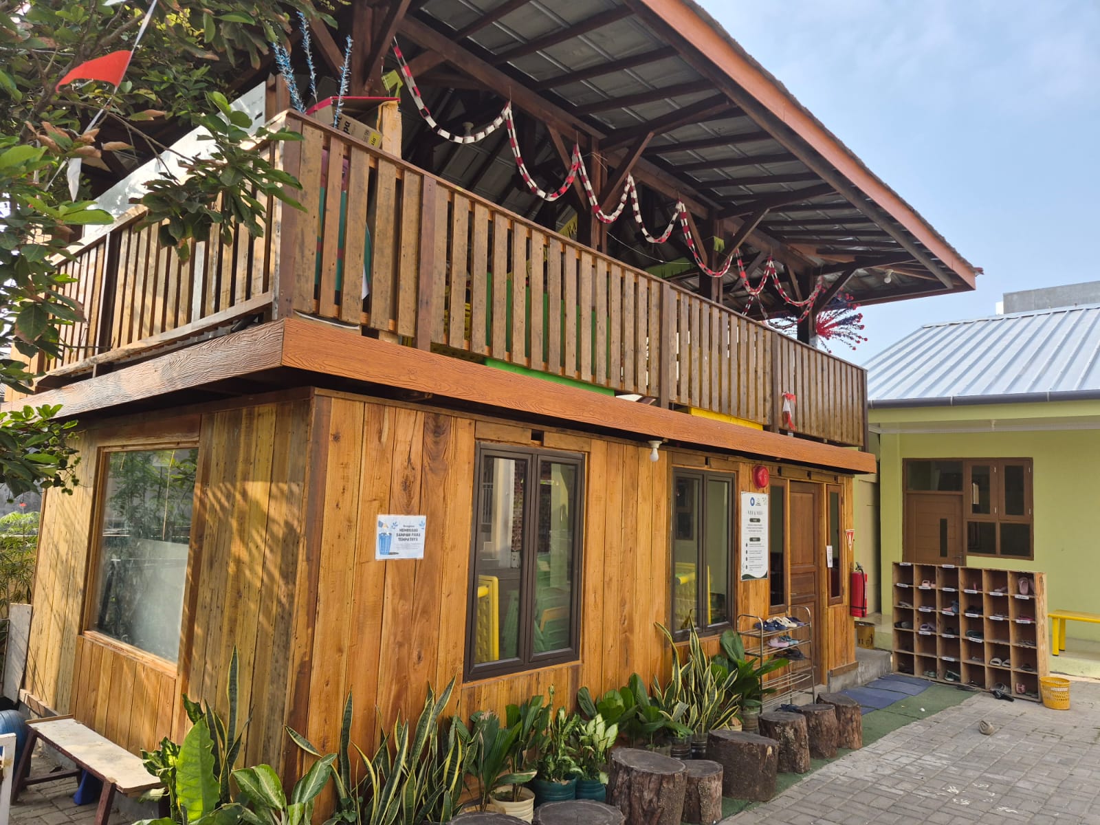Detail bangunan saung kayu dengan balkon dan tanaman hias