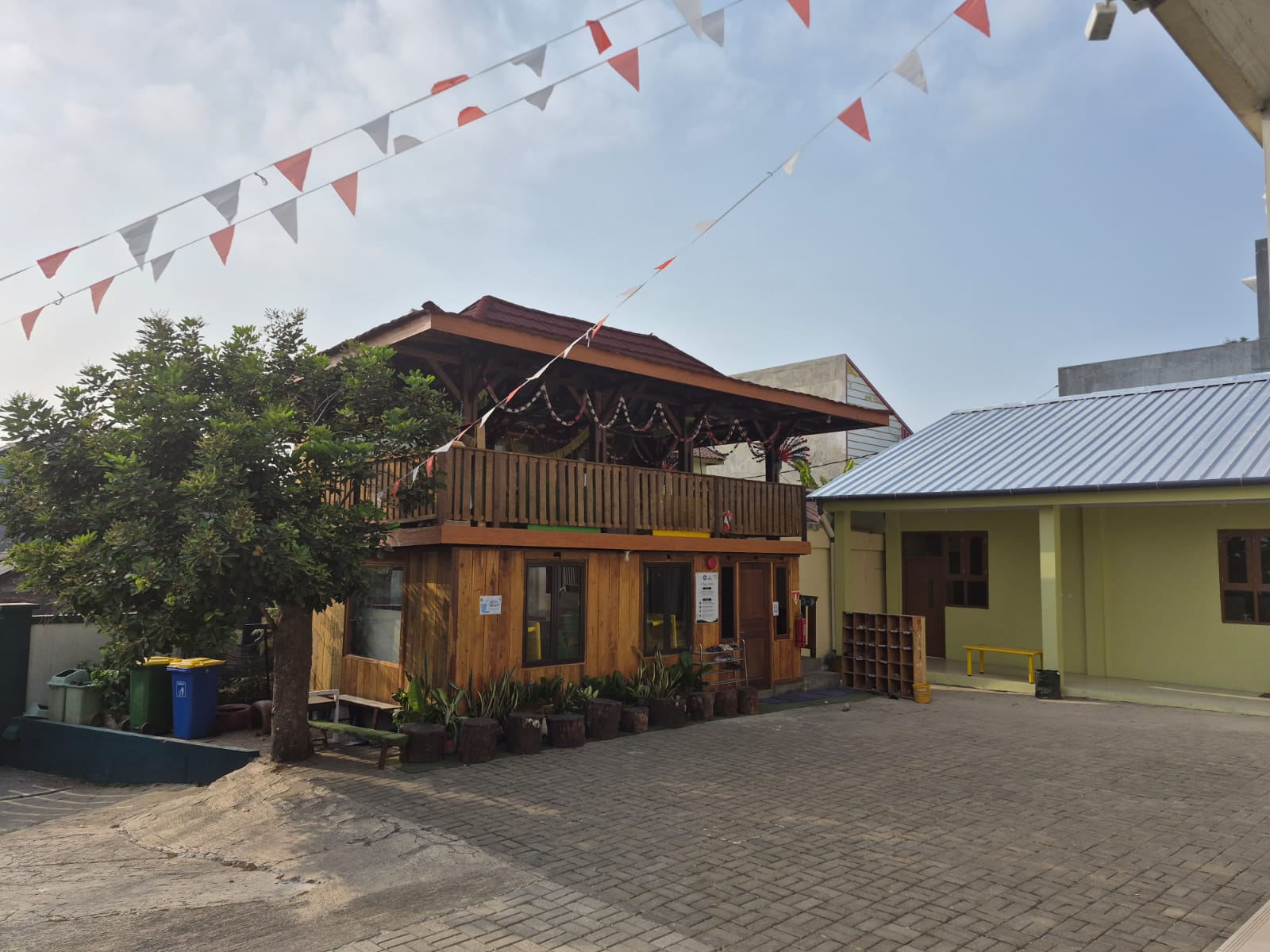 Saung kayu Saung Qur'an tampak dari samping dengan pohon rindang